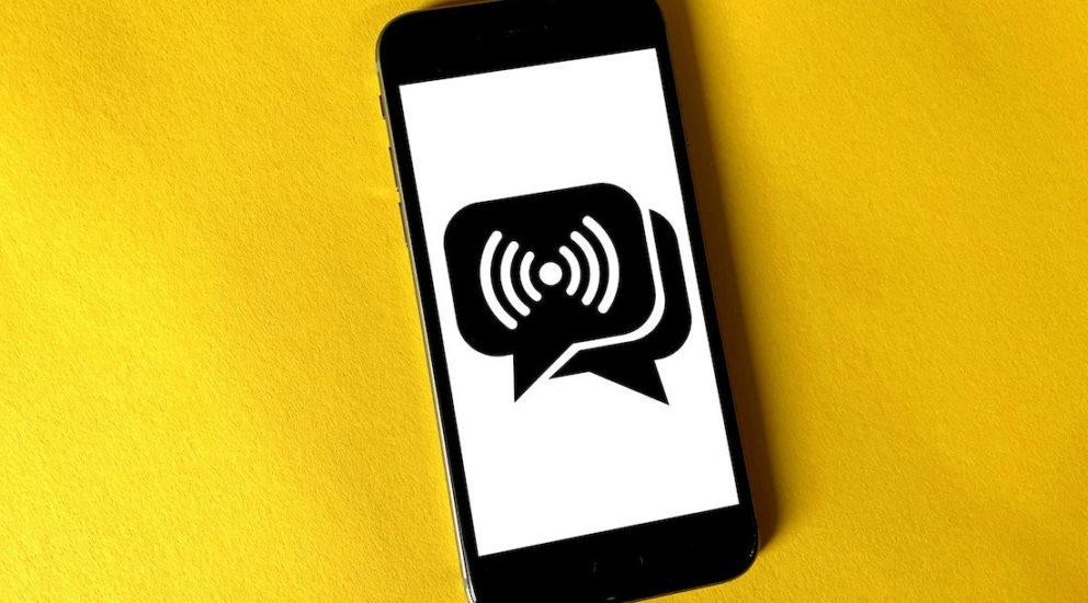 Schwarzes Smartphone auf gelbem Hintergrund mit einem Nachrichtensymbol auf dem Display